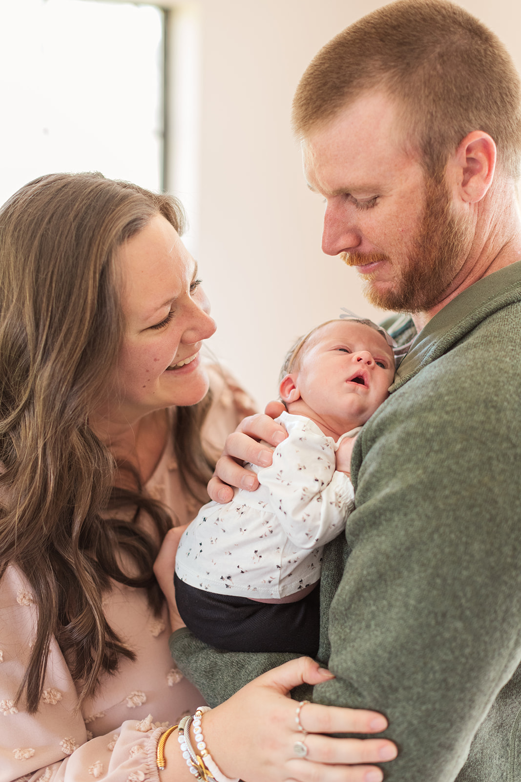 Tori and Tim smiling as they hold their daughter