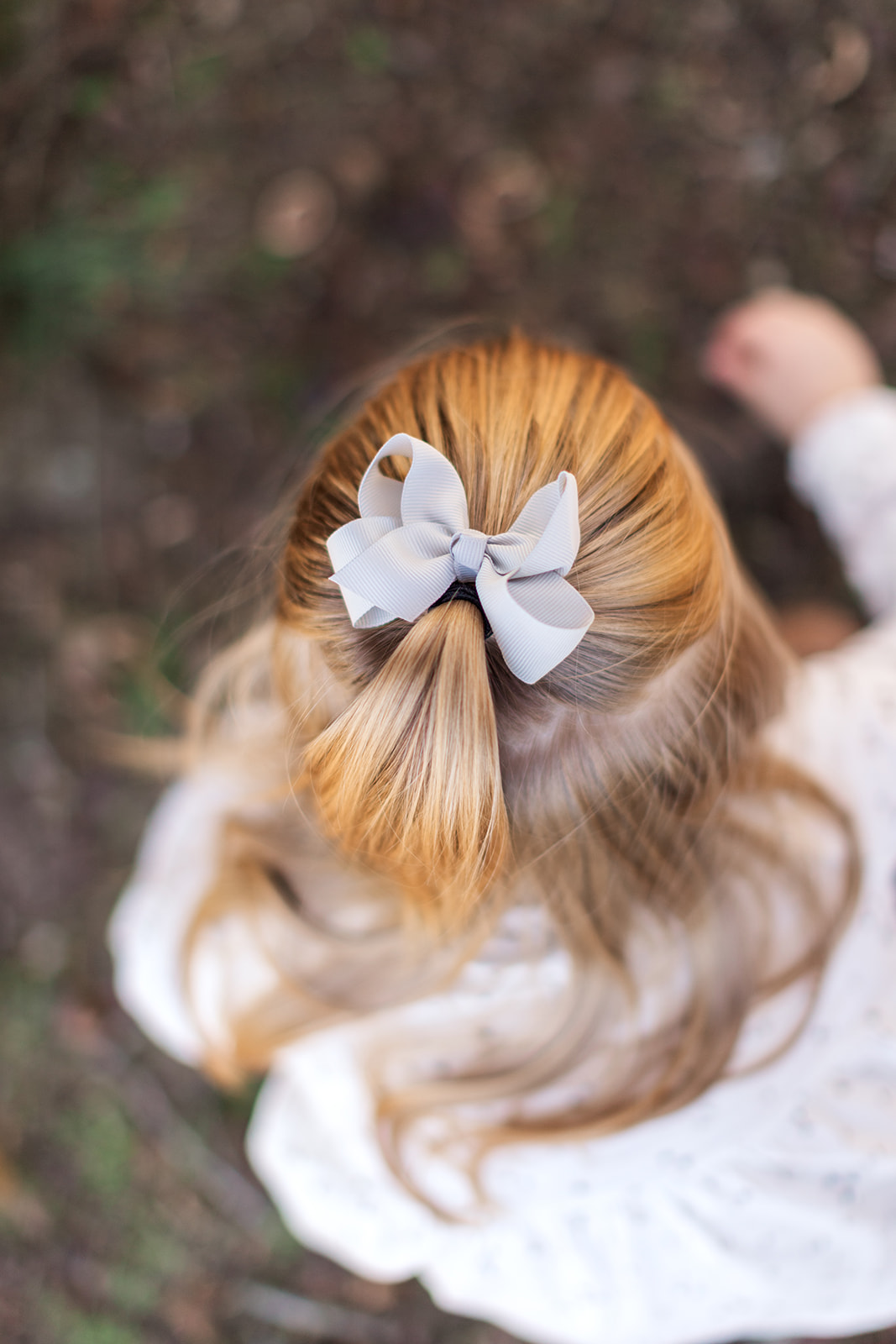 Close up of bow in older sister's hair while she plays in the dirt during newborn and family photo session - capturing the little moments, the moments you want to remember
