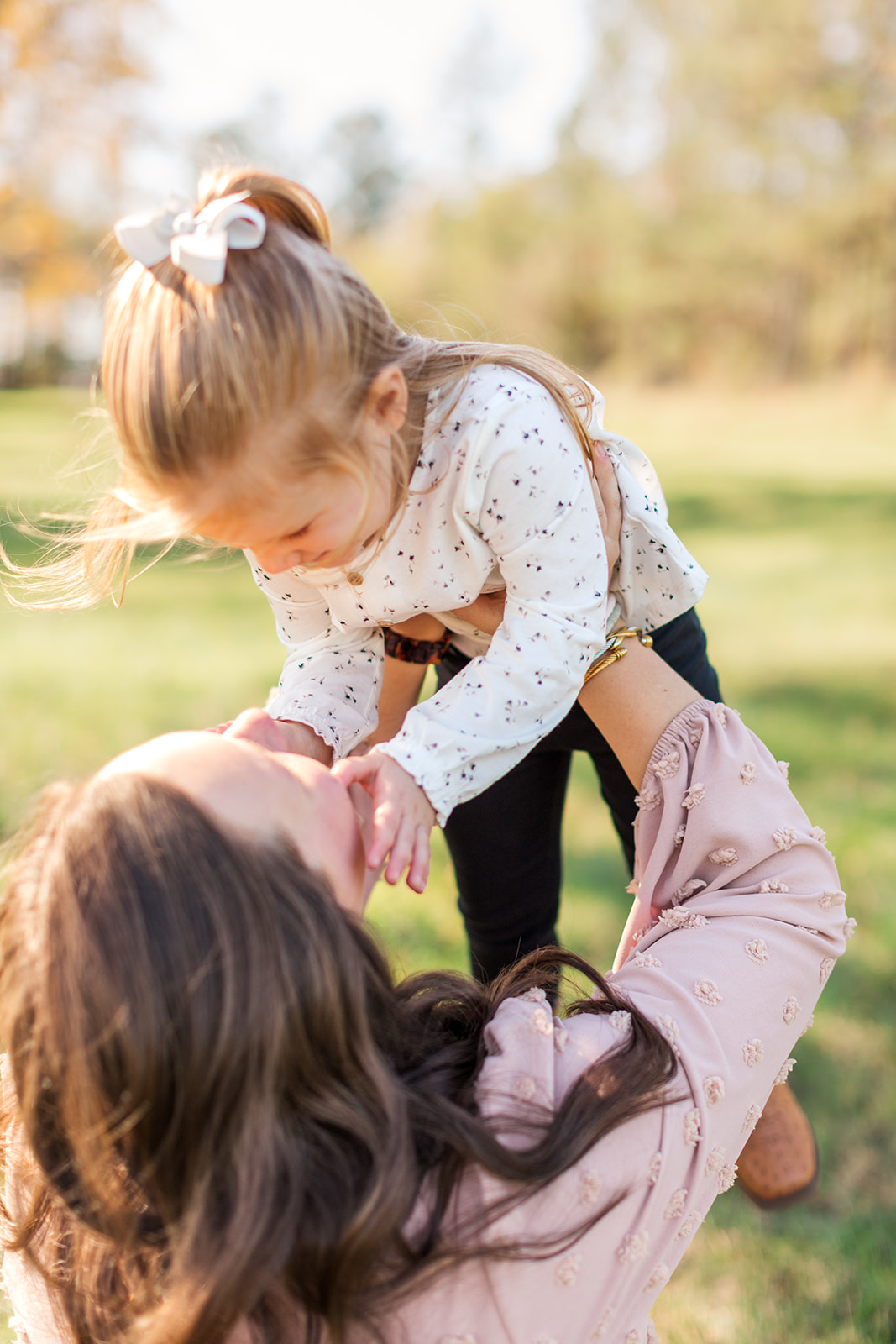 Mom holding big sister up in the air - a candid moment during a newborn and family photo session with a full-service photographer near Charlotte, NC