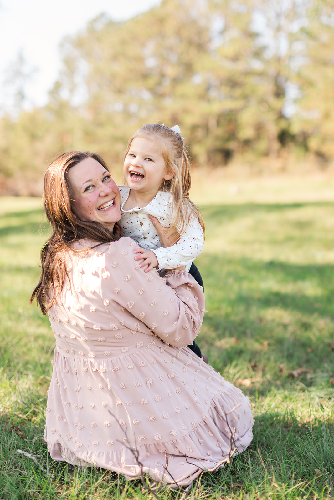 Mom and big sister laughing and hugging together during newborn and family photo session