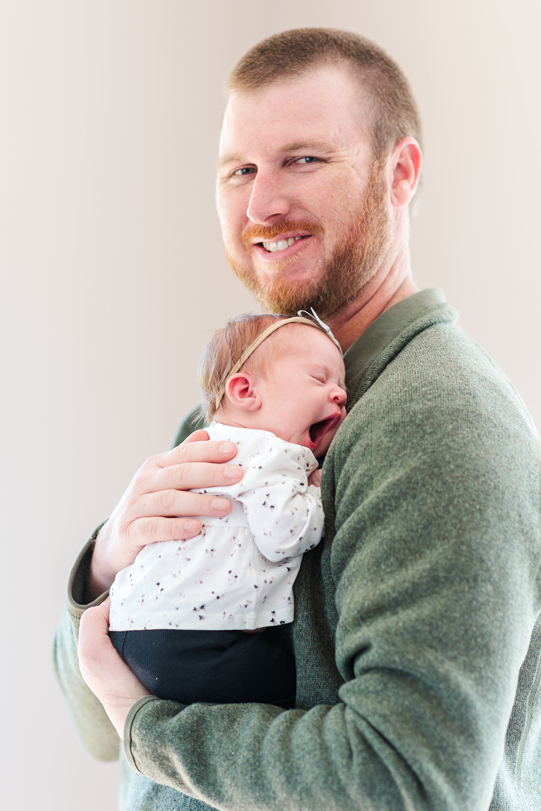 Perfect heirloom photo of dad holding yawning baby girl during newborn photo session with a full-service photographer.