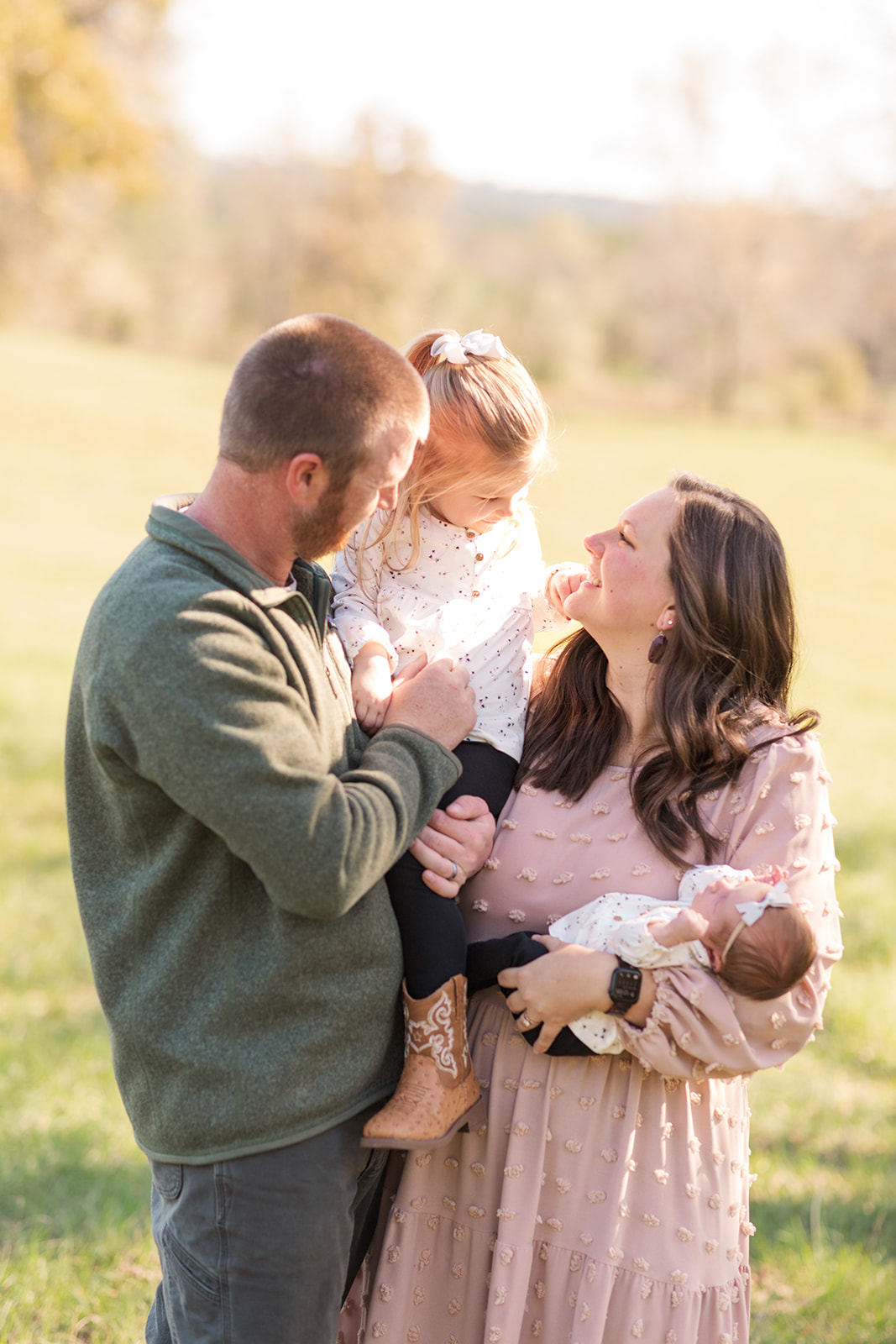 Family of 4 candid moment laughing and talking together outside during newborn photo session