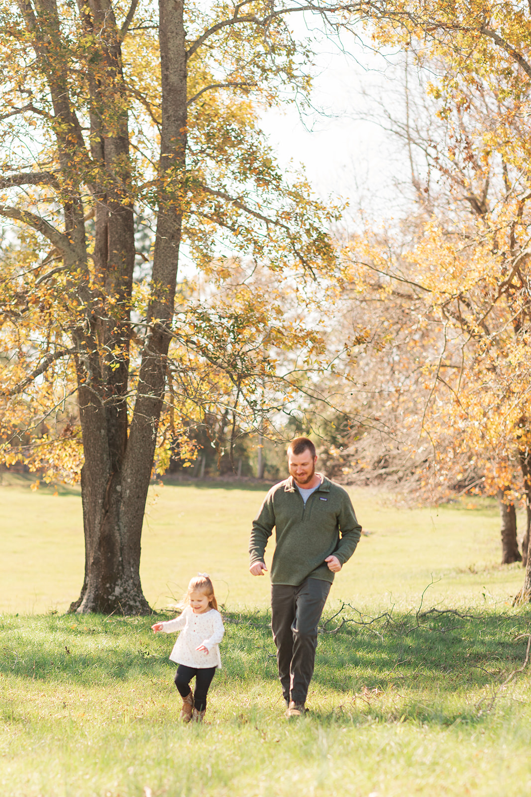 Dad running after older sister with trees in the background