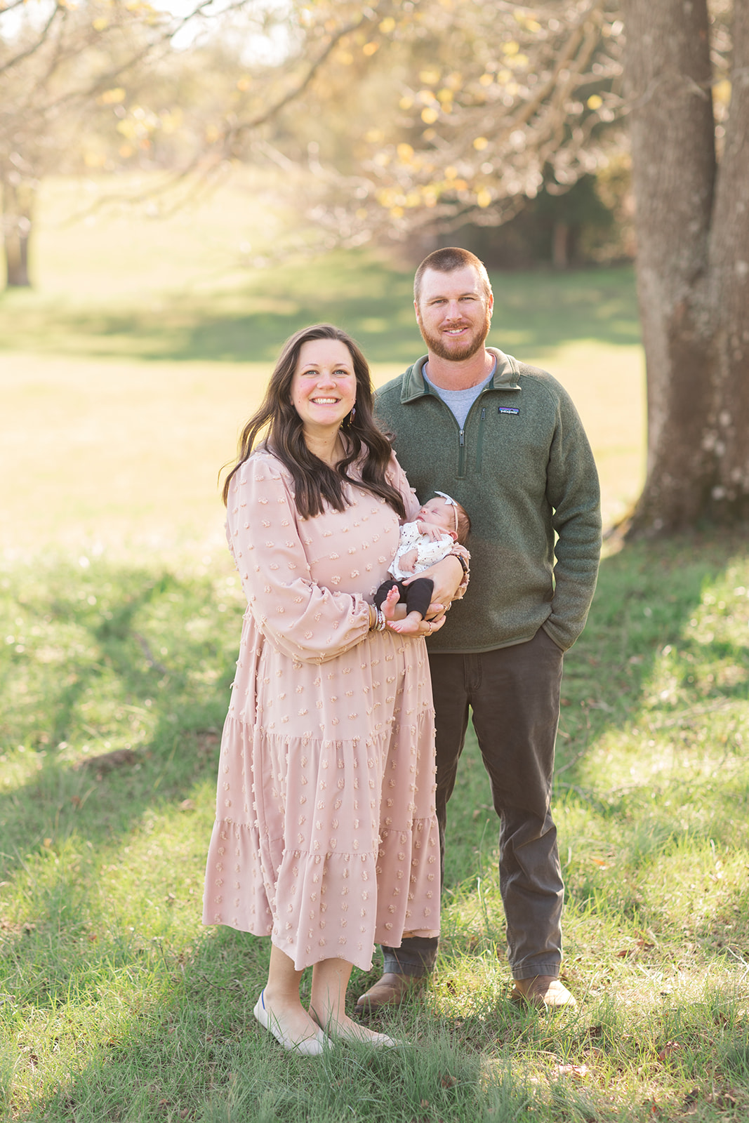 mom, dad and newborn smiling outside in natural light during newborn photography session