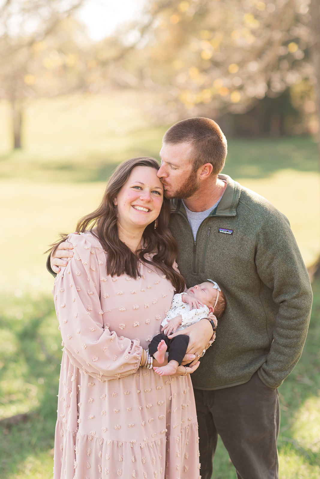mom, dad and newborn smiling outside in natural light during newborn photography session