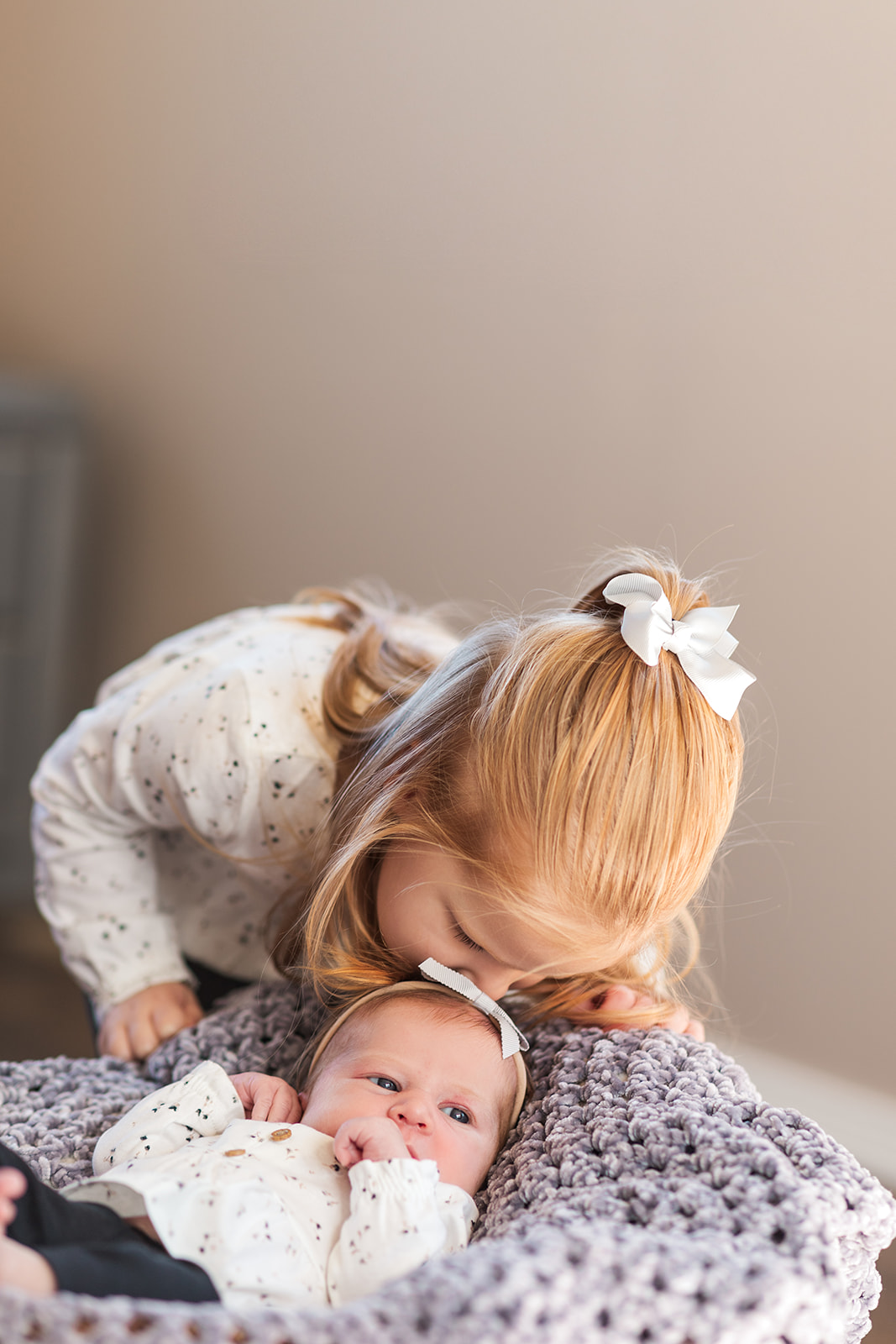 Big sister Addie kissing her baby sister’s head