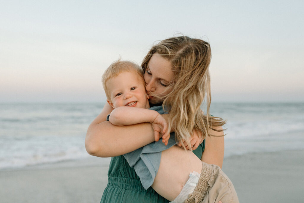 Mom twirling barefoot in the sand while holding baby