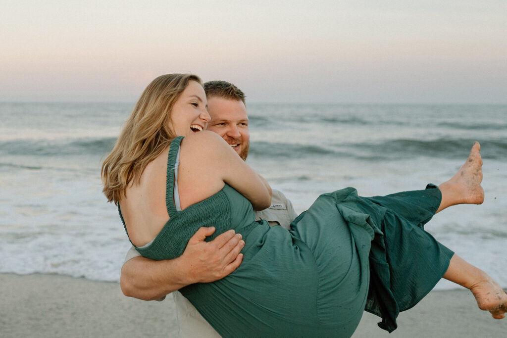 Dad holding mom and twirling around with ocean in the background