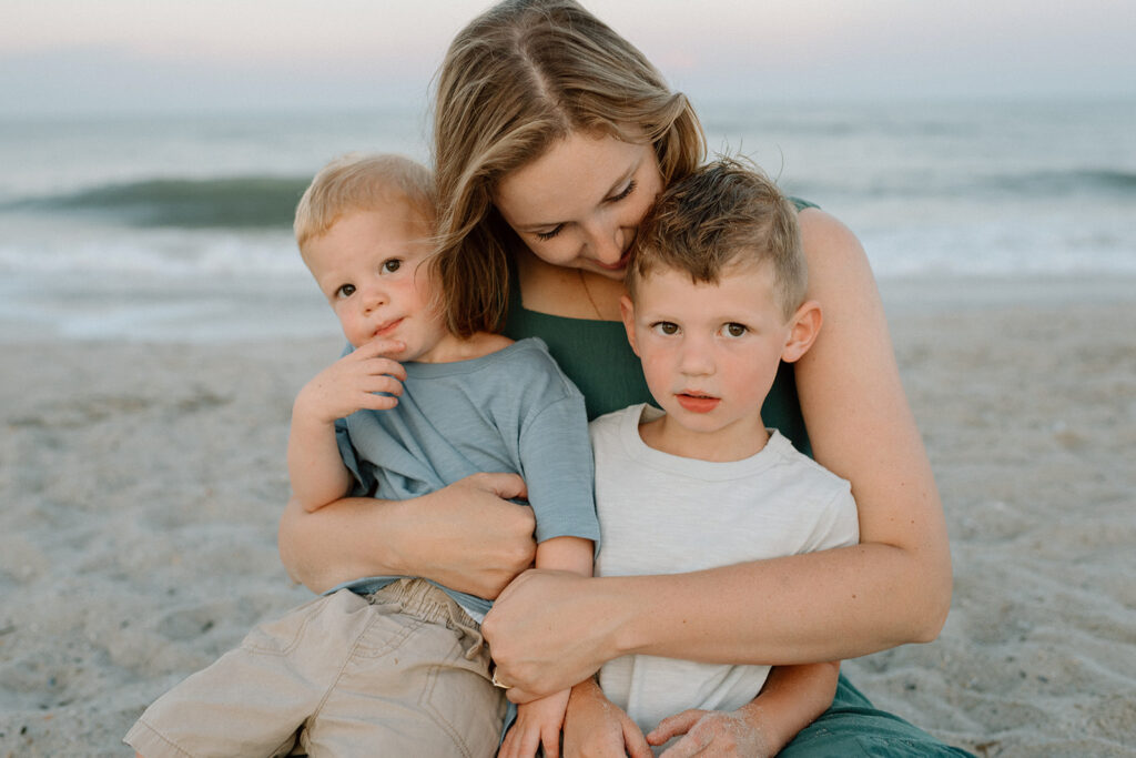 Sweet family hug captured in front of a soft pink sky