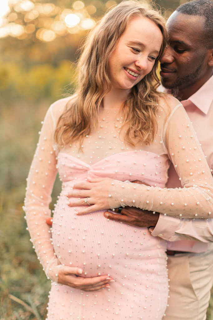 Backlit photo of couple wrapped in a gentle hug, glowing in soft golden light.