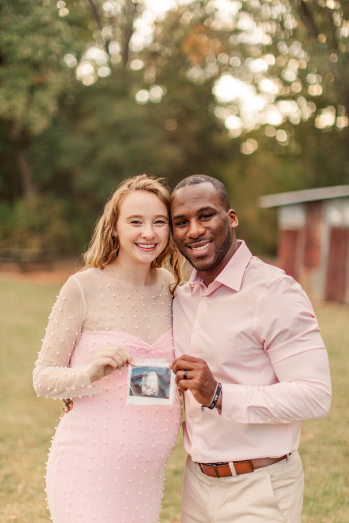 Couple embracing with ultrasound, glowing in golden light.