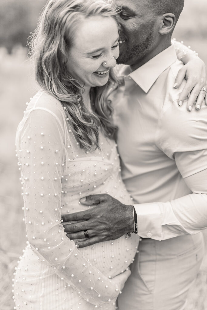 Maternity photo of couple laughing together under soft natural light