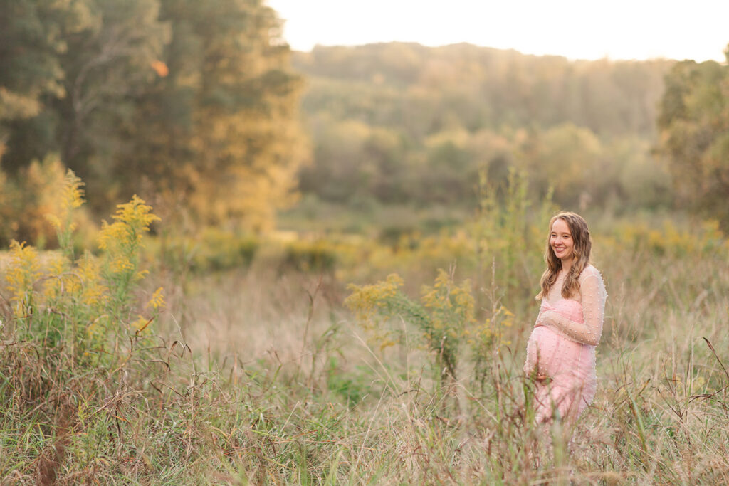Peaceful image of mom-to-be looking at her belly with nature in full bloom around her.