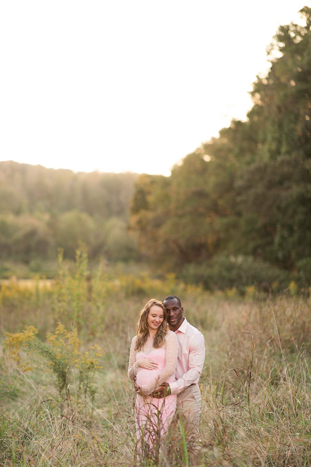 Maternity session with boyfriend holding girlfriend's belly at Fisher Farm in Davidson, NC at golden hour.