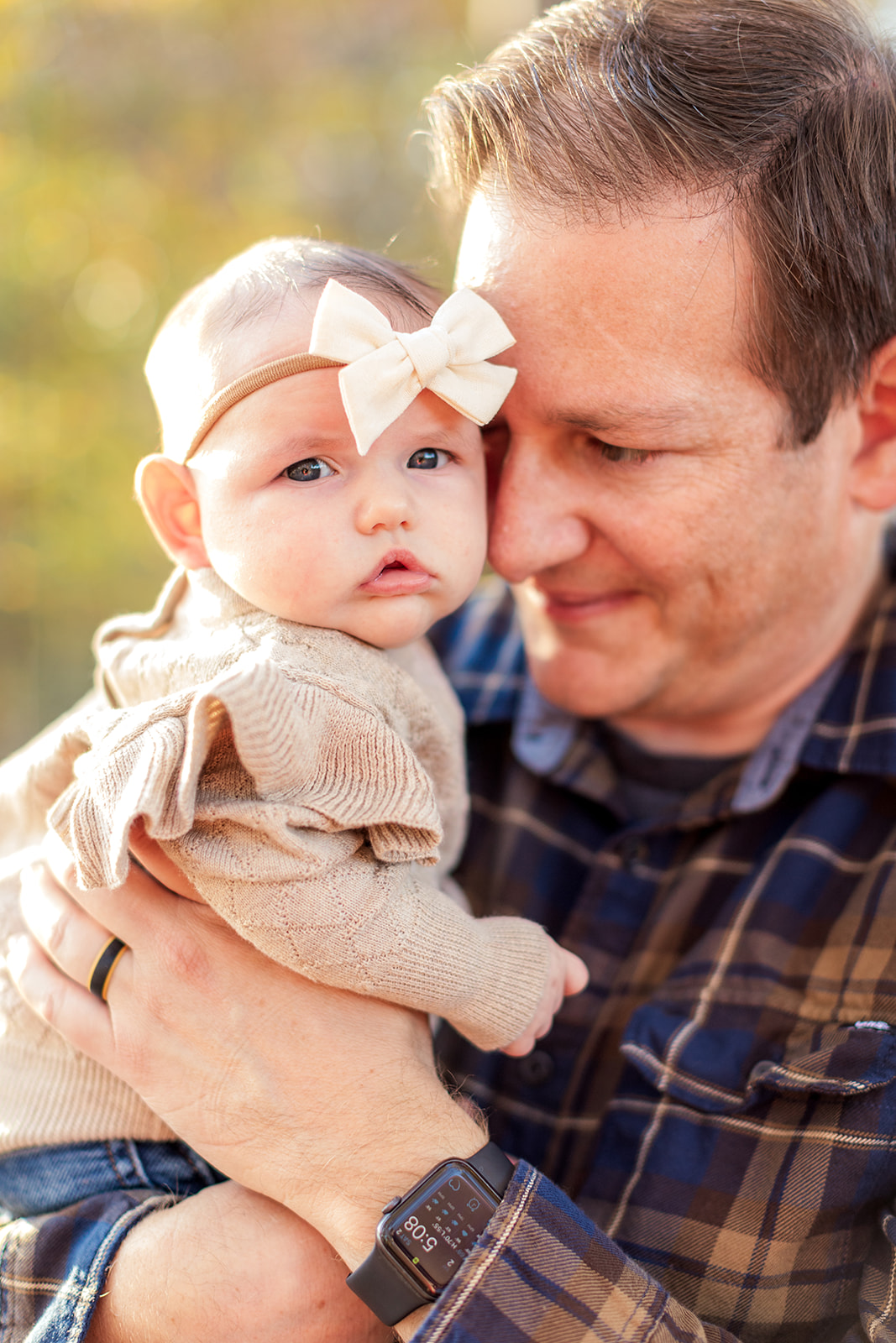 Newborn and dad snuggled up together with natural light behind them