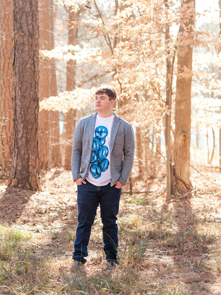 Laid-back senior pose in front of rustic forested backdrop