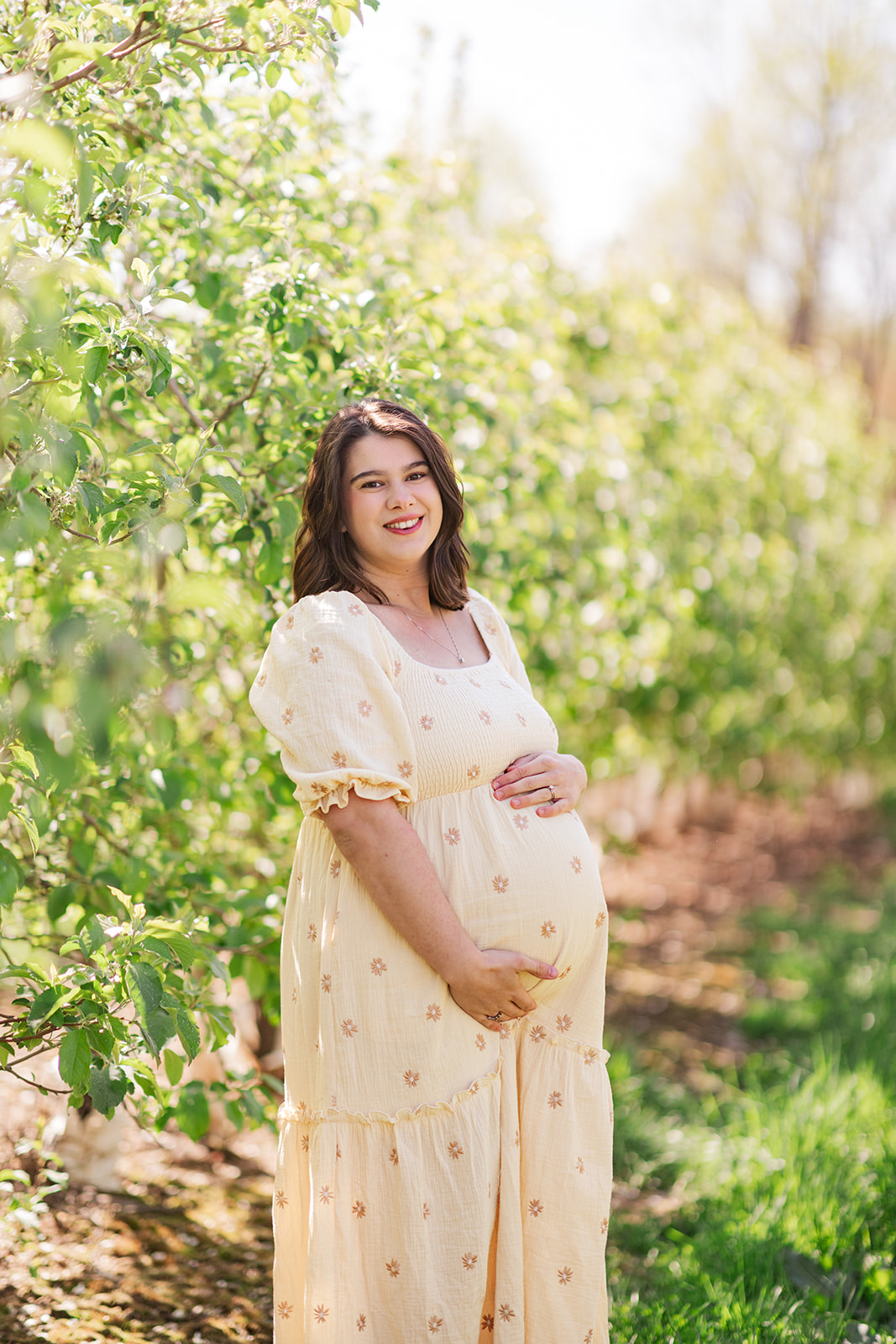 Joyful maternity photo of Abby in green orchard