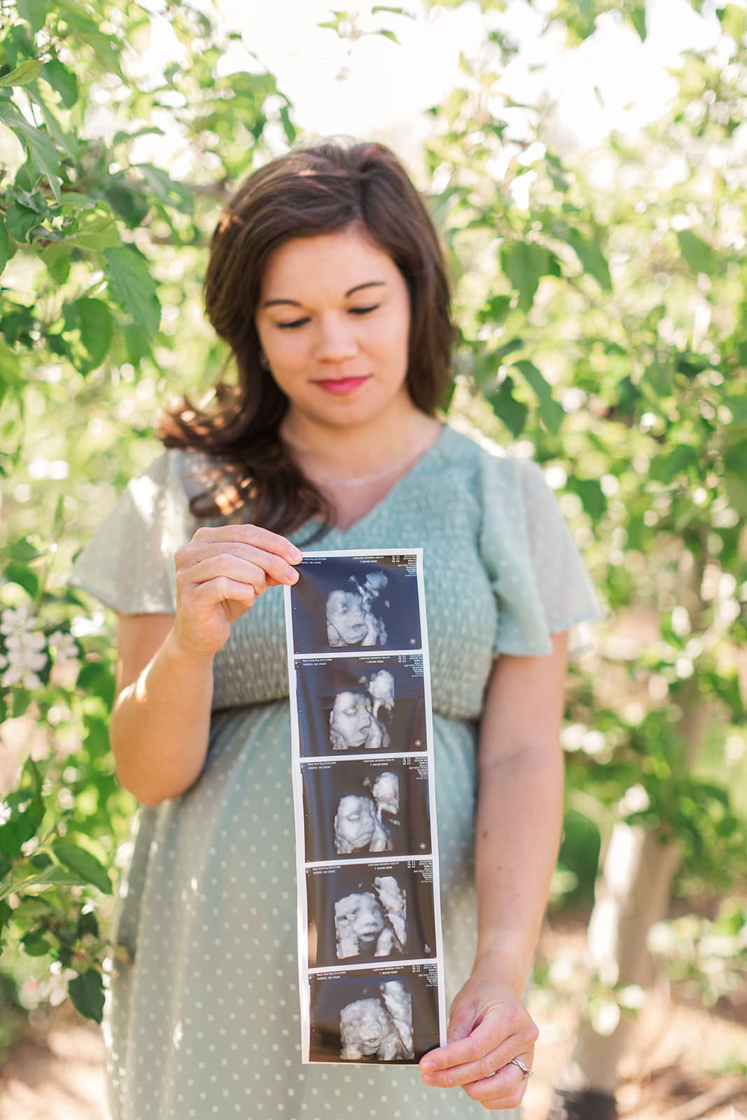 mom-to-be holding ultrasound pictures during maternity photo session near statesville, nc