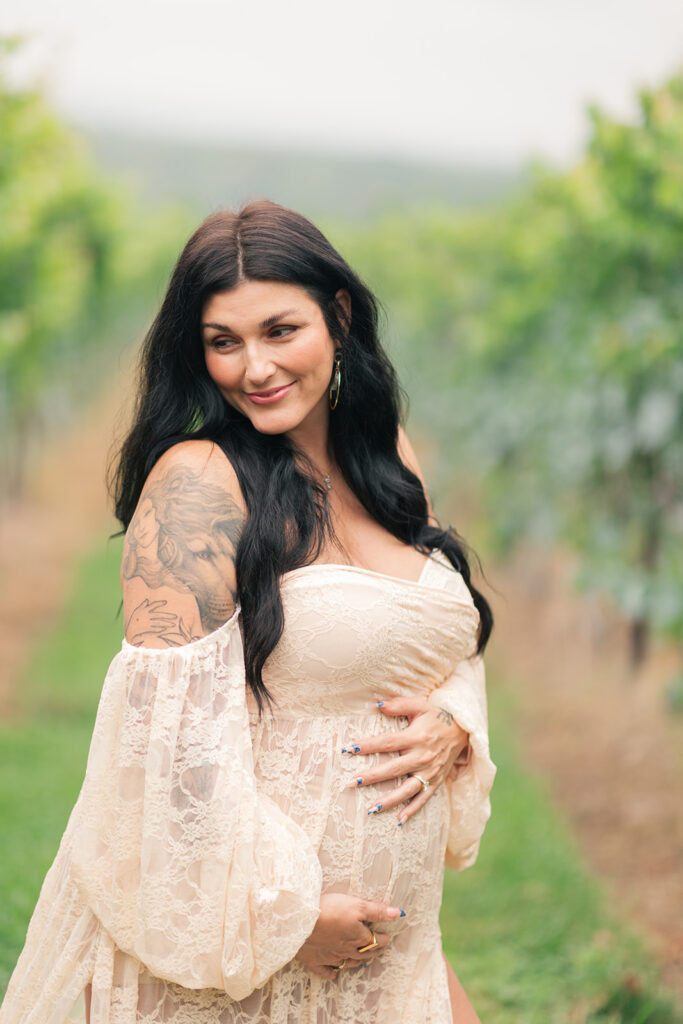 Expectant mother standing in grapevine rows during golden hour
