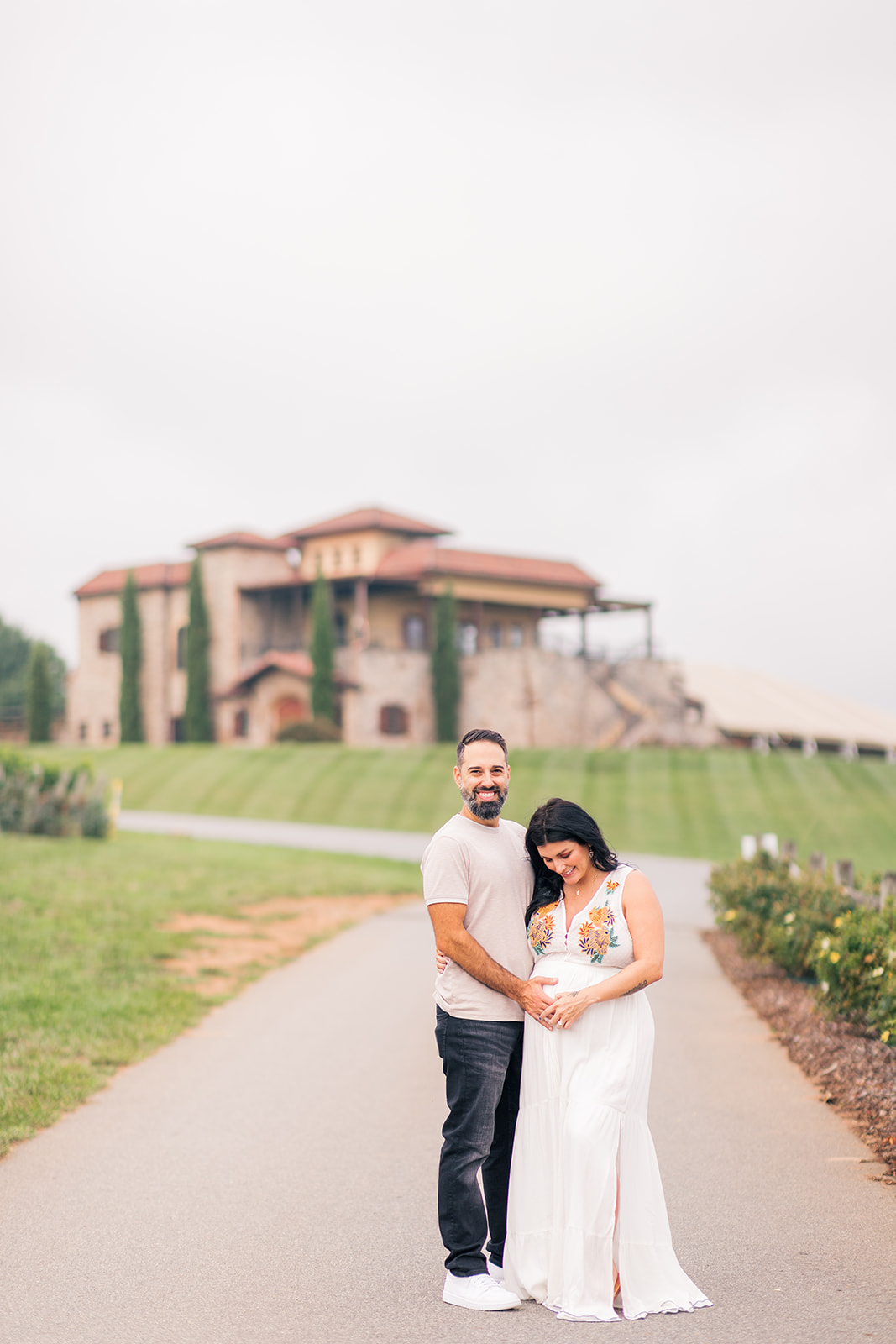 Husband holding wife's baby belly at a beautiful vineyard in Ronda, NC.