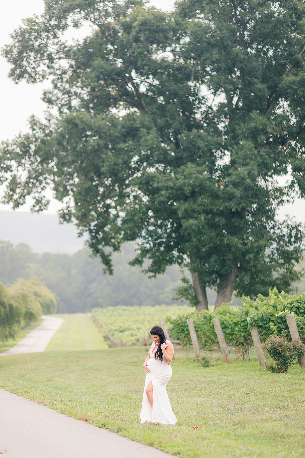 Mother-to-be in flowing dress walking between vineyard rows