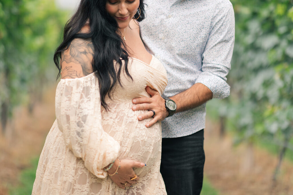 Felicia and Tim embracing in vineyard maternity session