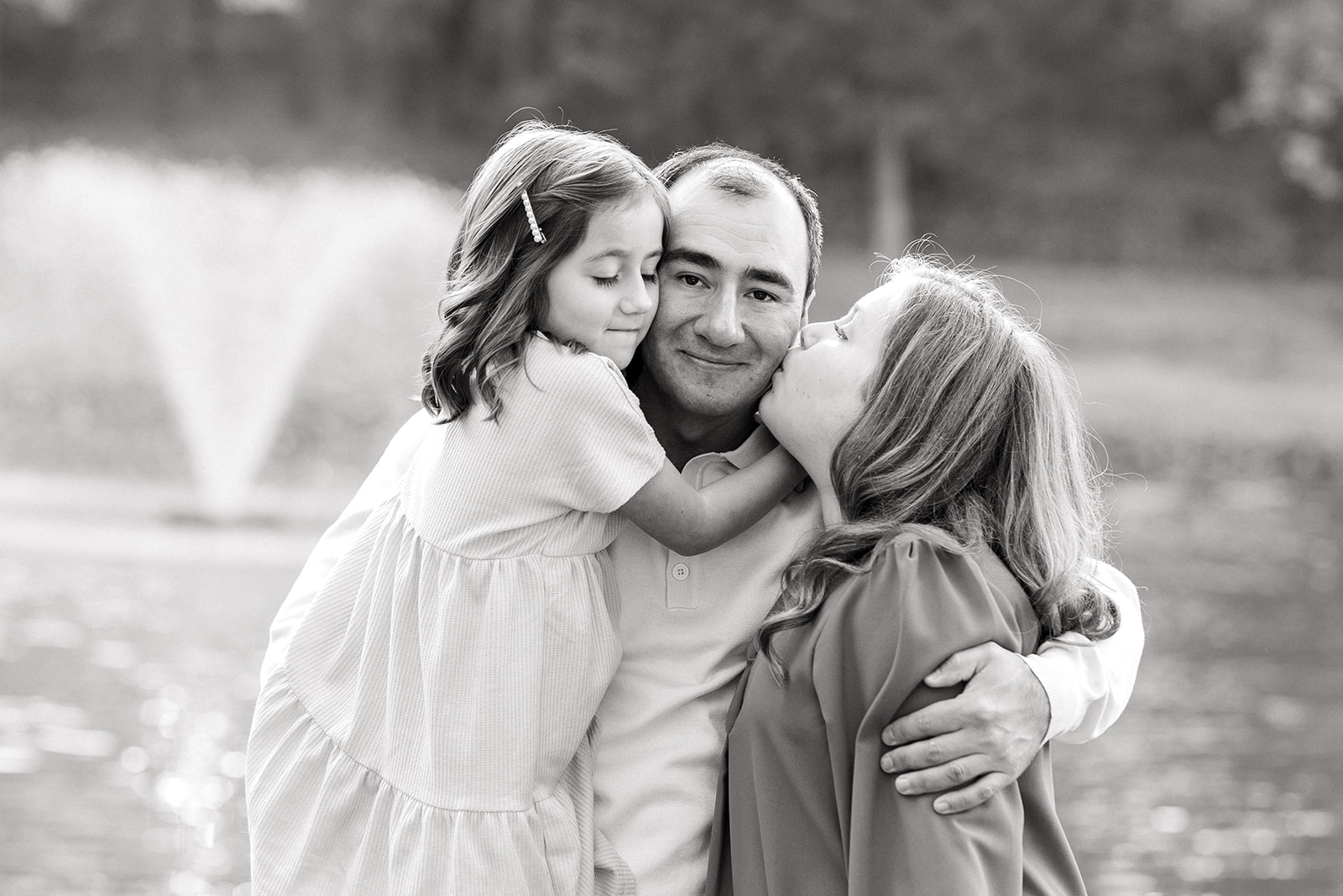 Close-up of siblings kissing dad during outdoor portrait session