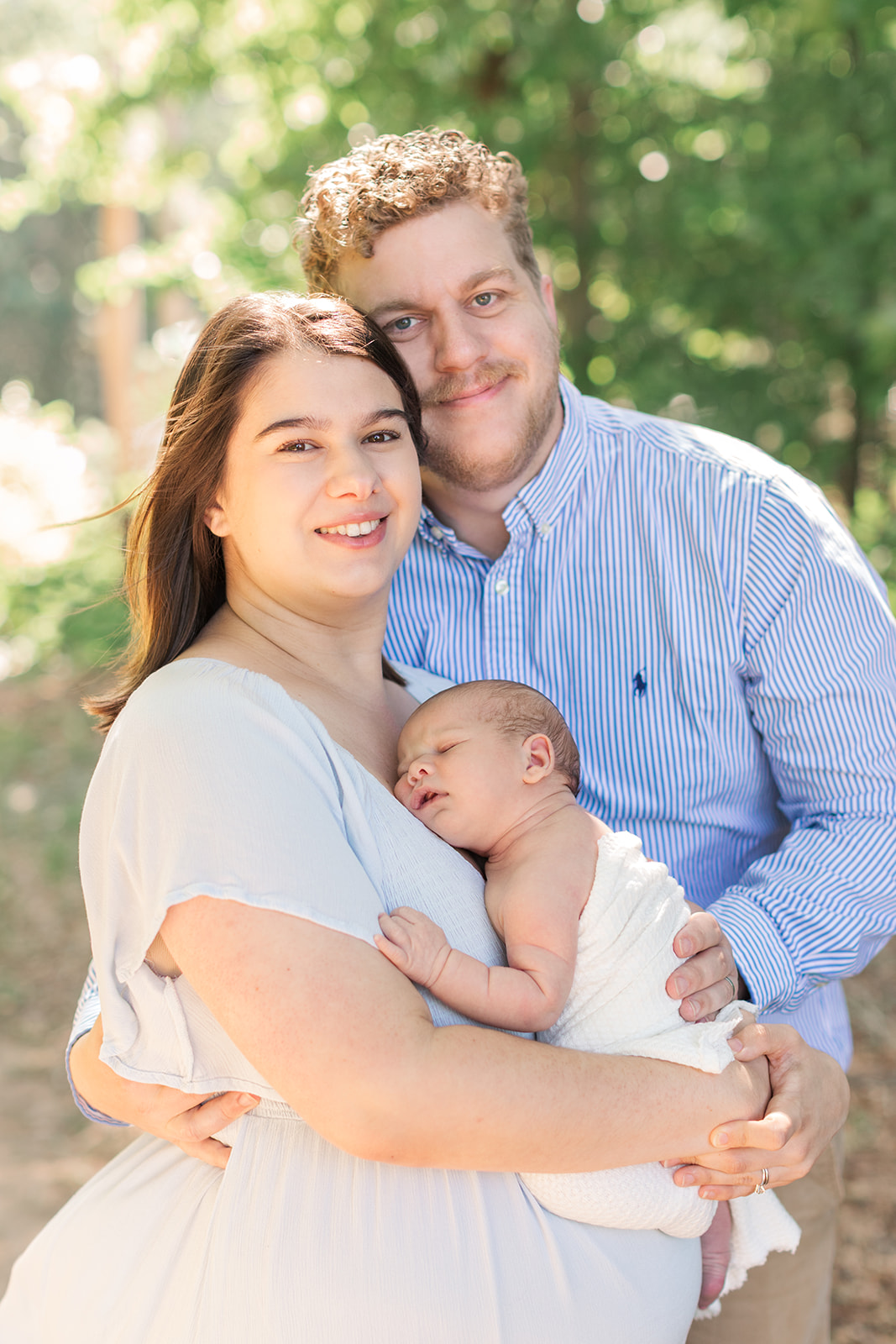 Father and mother gently holding newborn during peaceful spring morning session