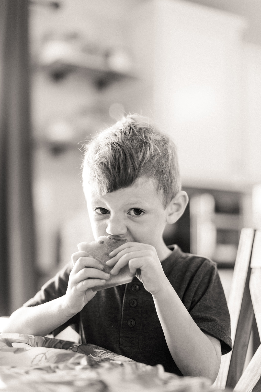 Black and white photo of Ryder happily eating a sandwich at age four