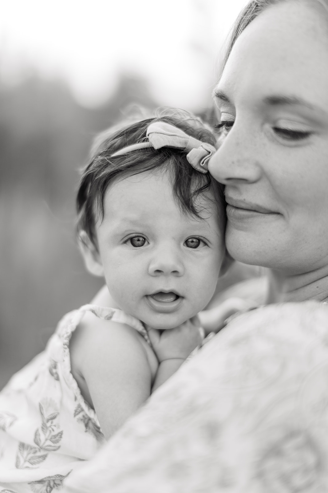 Emotional moment of mom holding baby while standing beside new home