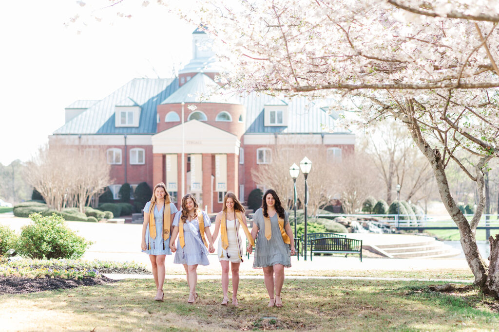 Friends linking arms walking down a campus path