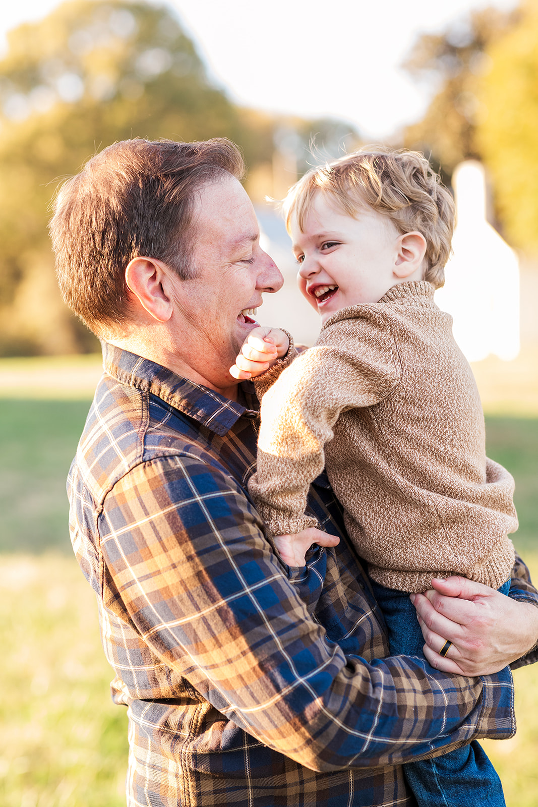 Dad holding toddler with sunlight coming through the trees