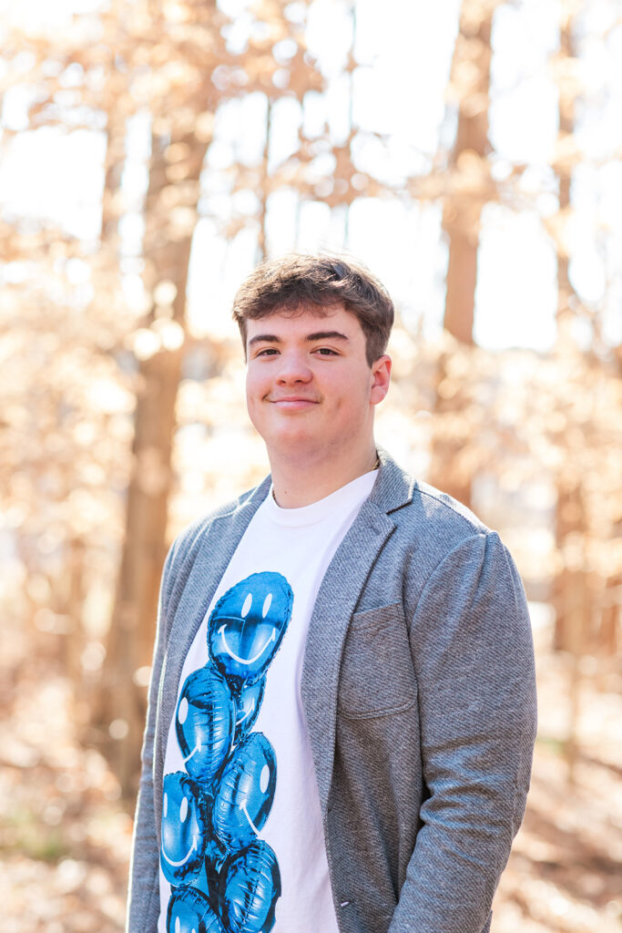 Portrait with blue balloons on shirt, wooded area in background