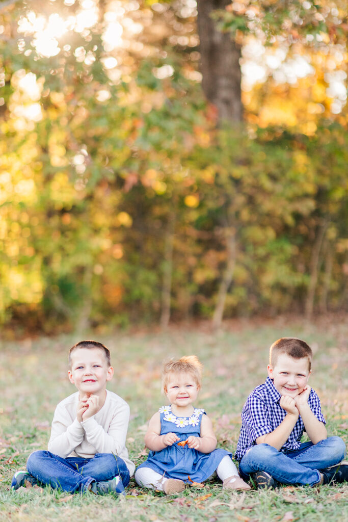 Photo of three siblings sitting on a blanket looking at the camera in the fall in North Carolina.