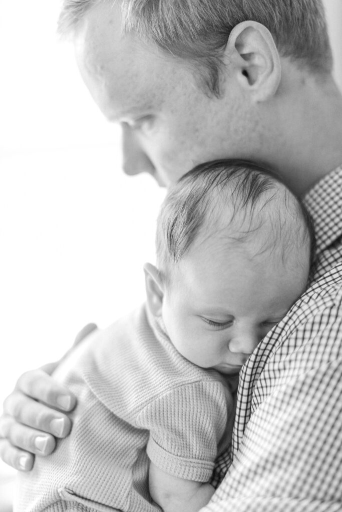 Dad holding sleeping newborn during in-home newborn session near Charlotte, North Carolina.