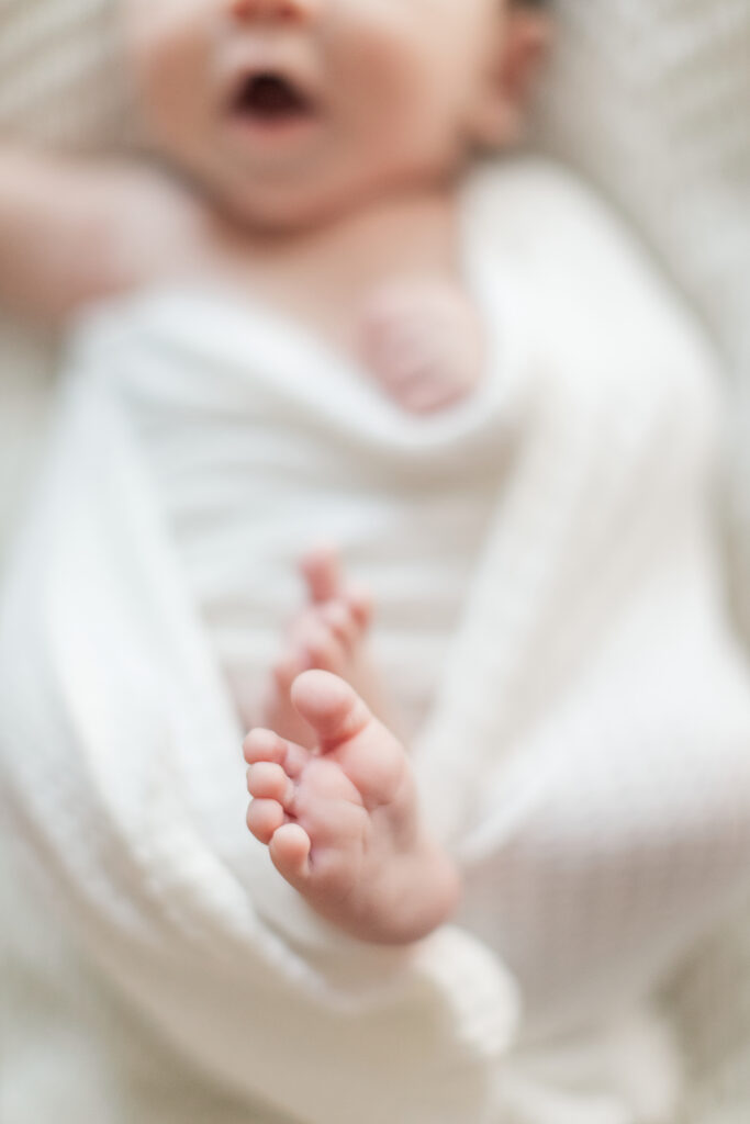 Newborn baby toes swaddled in white near a Charlotte newborn photography studio.