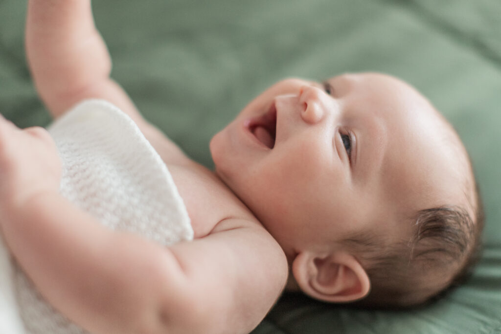 Baby laughing at camera on bed near Huntersville, North Carolina.