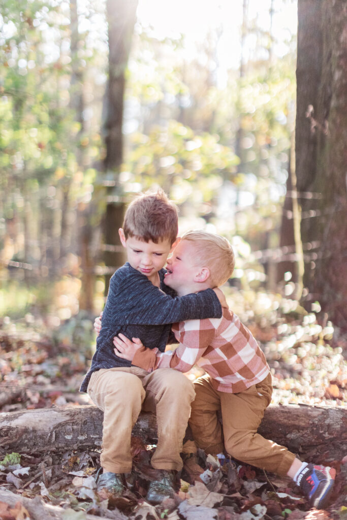 Boys hugging in fall field after mom learns about faith after miscarriage. 