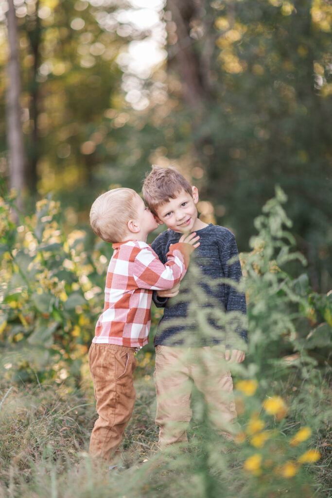Boys whispering to each other in a fall field in North Carolina. 