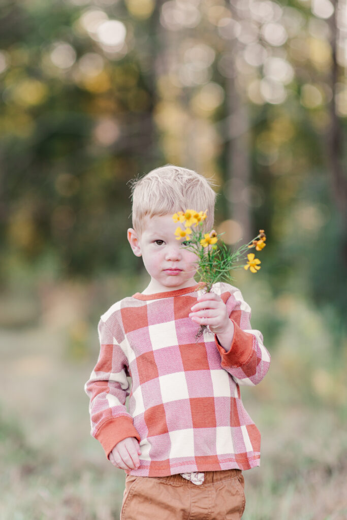 Two year old boy hiding in the flowers after mom learns about faith after miscarriage. 