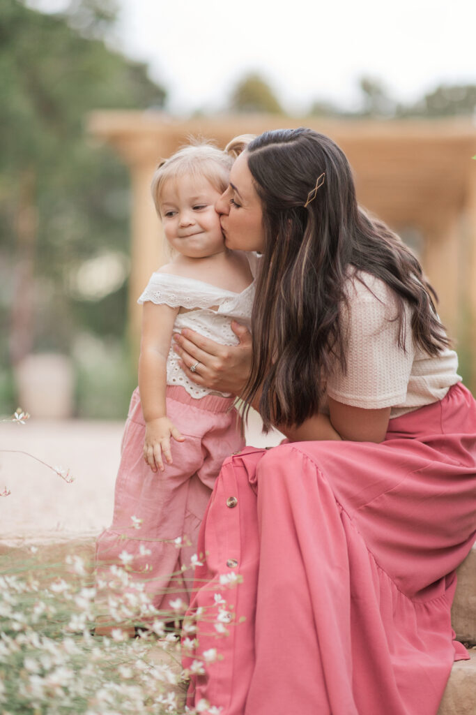 Mom kissing baby girl's cheek during family photos. 