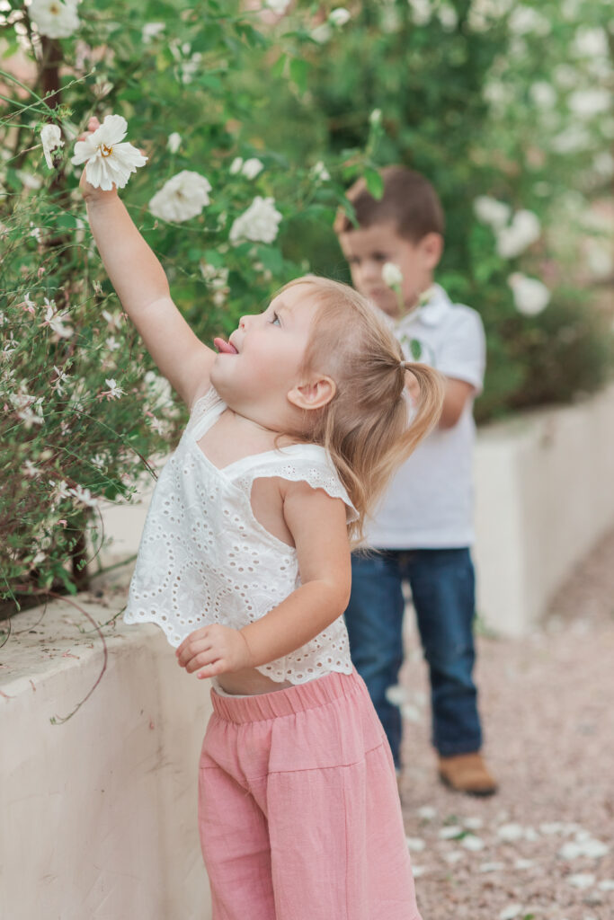 Girl reaching for flower and sticking her tongue out in a natural candid way in Taylorsville, North Carolina.