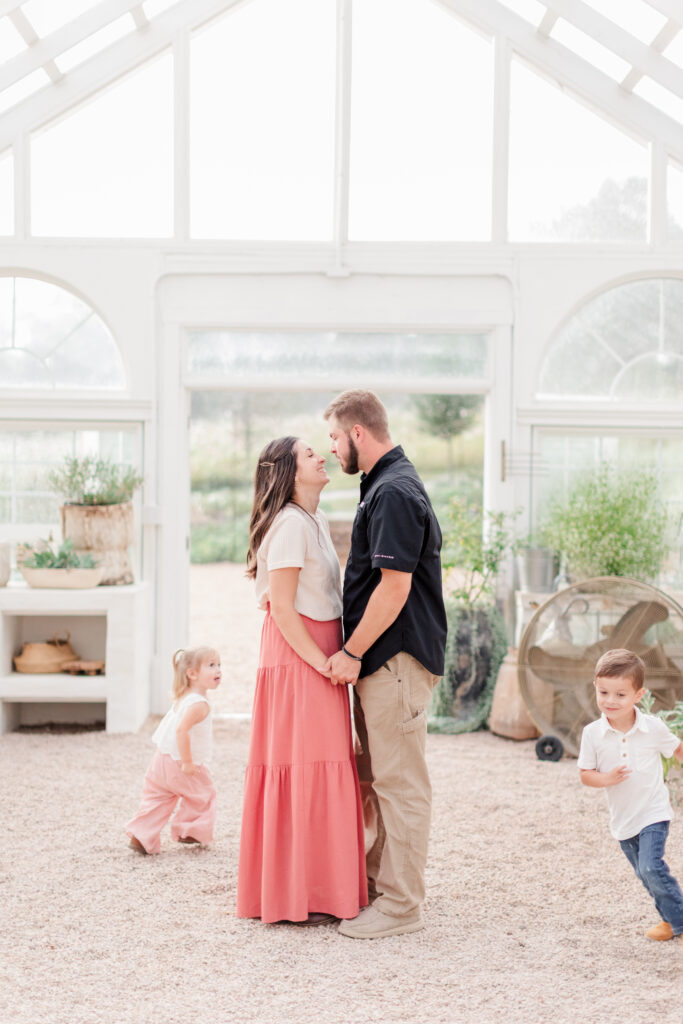 Parents looking at each other in the Greenhouse in Taylorsville, North Carolina as the kids are running in circles around them. 