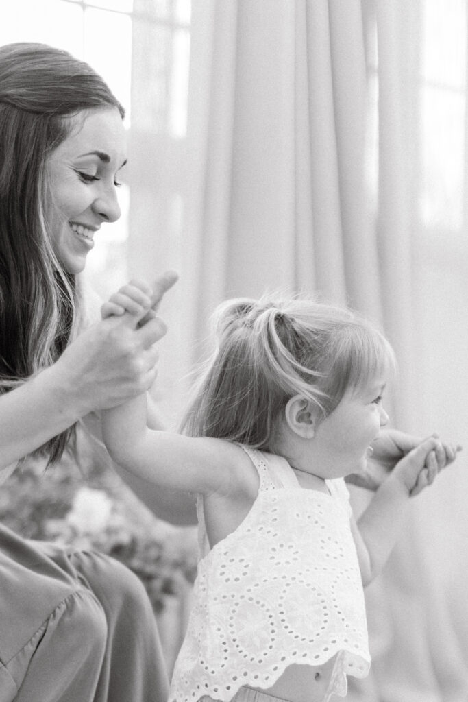 Mom holding little girl's hand and smiling genuinely in a greenhouse in North Carolina. 