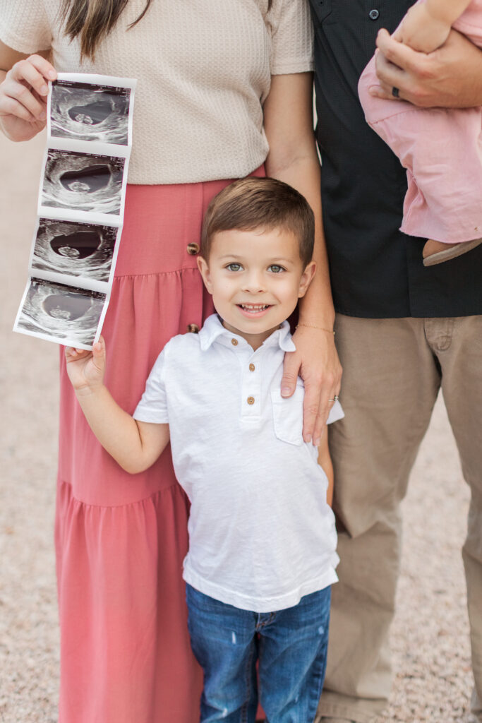Little boy holding sonogram picture and smiling. 