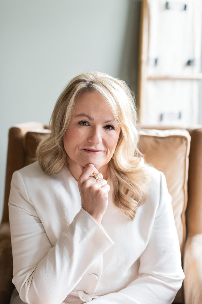 Headshot of Allen Tate realtor Roxanna Levan looking straight at camera holding her chin in a chair near Mooresville, North Carolina. 