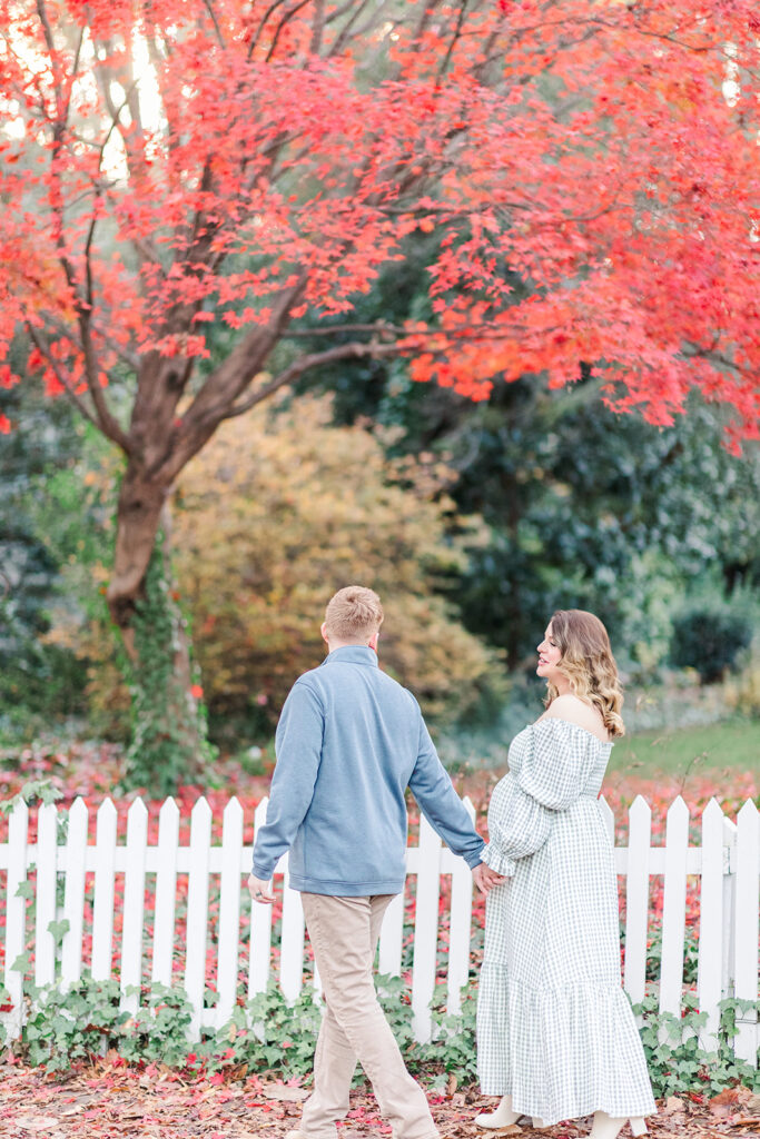 Husband and wife holding hands and walking during fall with outdoor maternity photographer near Statesville NC. 