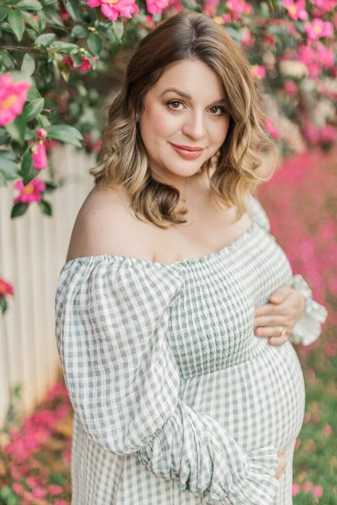 Pregnant mom looking at camera holding belly during her maternity session at Old Salem, North Carolina. 