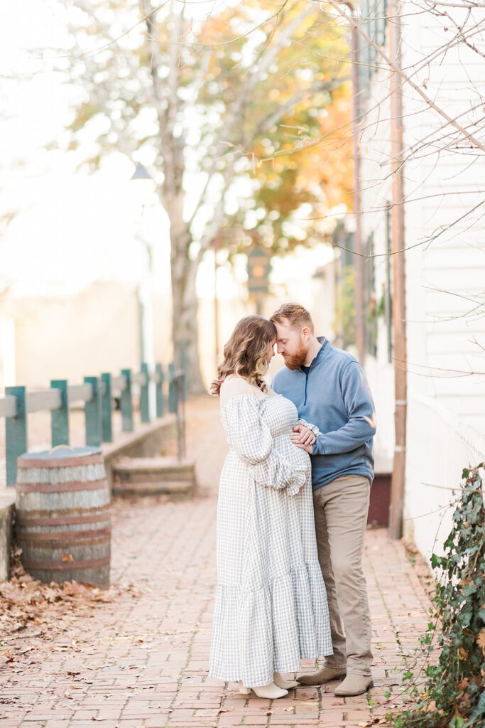 Mom and Dad putting heads together holding baby bump at Old Salem, North Carolina. 